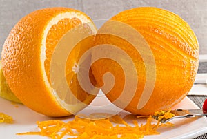 Scratched orange and thin curls of orange peel on white plate