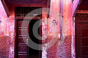 Scratched pink walls and red doors on the streets of Marrakesh