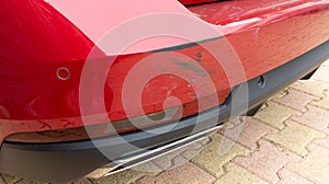 Scratched red car rear bumper in minor accident street vehicle damaged in collision