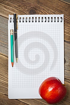 Scratchpad for taking notes, a pen, a pencil and an apple