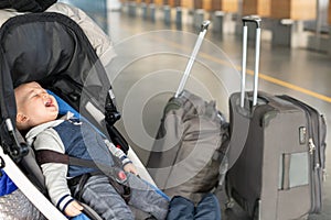 Screaming baby boy sitting in stroller near luggage at airport terminal. Child in carriage near check-in desk counter. Children