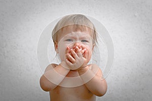 Screaming baby covering mouth by hand