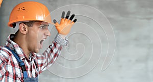 Screaming builder in helmet. Young man construction worker in hard hat crazy and mad shouting and yelling with