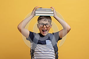 Screaming cute boy schooler with book on his head