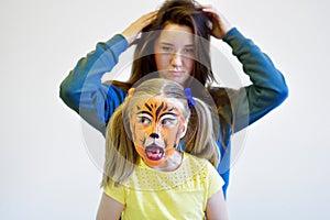 Screaming girl with painted tiger face and her mother
