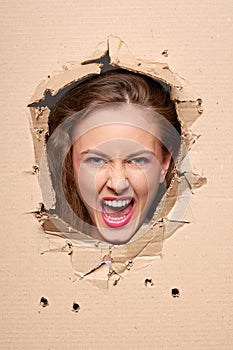 Screaming girl peeping through hole in paper