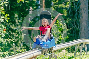 Screaming girl riding mountain roller coaster with outstretched arms