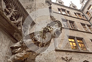 Screaming grotesque carved figure projecting from the gutter of building, Stone gargoyle on building in Bavaria, Germany