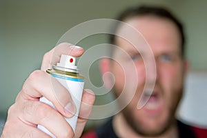 Screaming man blurred out of focus in the background hand in the foreground with insect spray