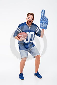 Screaming man fan in blue t-shirt holding rugby ball.