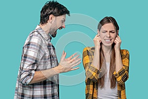 Screaming man in profile, girl covering her ears with her hands.