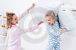 screaming mother and daughter having fun and fighting with pillows