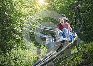 Screaming teen girl riding downhill on an outdoor roller coaster on a warm summer day.