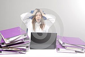 Screaming woman at desk with laptop and folders. Female entrepreneur suffers from nervous breakdown caused by fatigue, too much