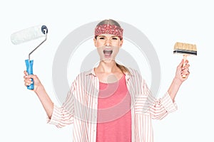 screaming woman in headband holding paint roller and paint brush