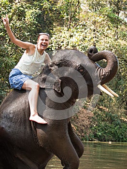 Screaming woman sits riding on young elephant that had risen on his hind legs and wrapped his trunk