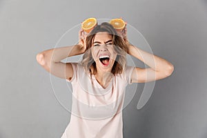 Screaming woman in t-shirt having fun and playing with oranges