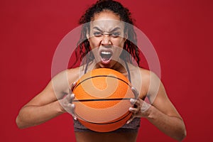 Screaming young african american sports fitness basketball player woman in sportswear working out isolated on red