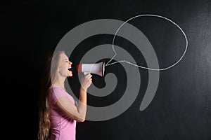 Screaming young woman with megaphone near drawn speech bubble on dark background
