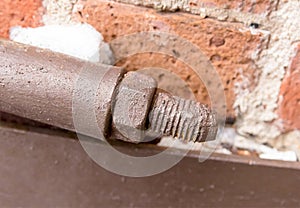 Screed bolt brown swirling nut long stem piece of construction metalwork weathered old on brick wall background loft style grunge