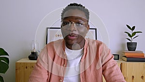 Screen view of young Black man waving hand and talking during a video call looking at camera. 4k video.