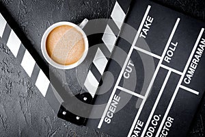 Screenwriter desktop with movie clapper board dark background top view