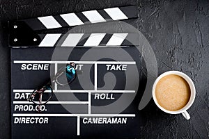 Screenwriter desktop with movie clapper board dark background top view