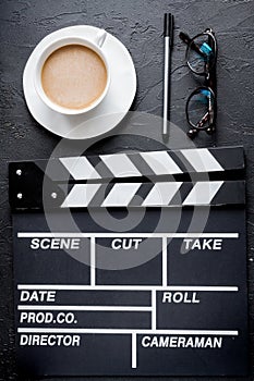 Screenwriter desktop with movie clapper board dark background top view