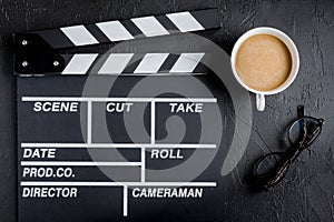 Screenwriter desktop with movie clapper board dark background top view