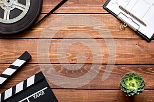 Screenwriter desktop with movie clapper board wooden background top view