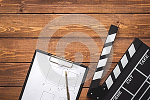 Screenwriter desktop with movie clapper board wooden background top view