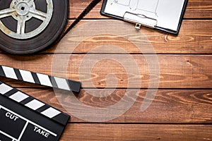 Screenwriter desktop with movie clapper board wooden background top view