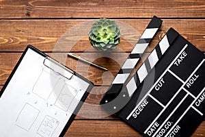 Screenwriter desktop with movie clapper board wooden background top view