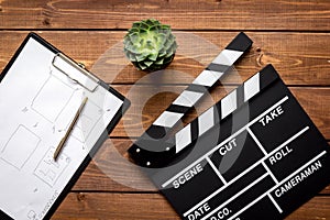 Screenwriter desktop with movie clapper board wooden background top view