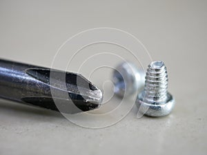 Screw and black iron Screw Driver on ground