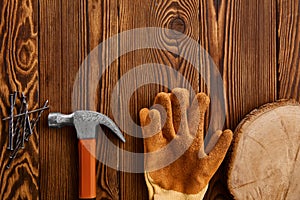 Screw nails, hammer and glove on wooden background