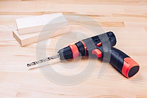 Screwdriver and drill. The drill drills a wooden block. Carpenter\'s workshop