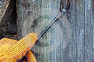 Screwdriver in hand and bent nail in a wooden wall