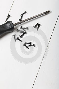 A screwdriver and a handful of screws. On white background