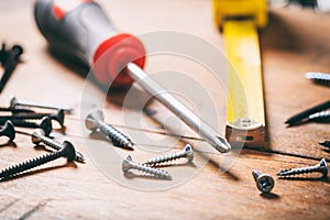 Screwdriver and nails on wooden background