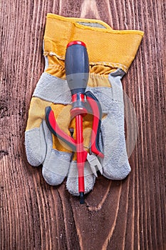 Screwdriver nippers and protective glove on wood