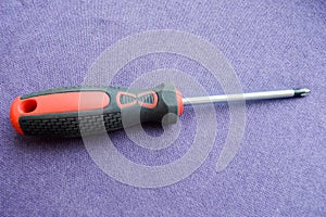 Screwdriver with rubberized red-black handle and black tip, cross-shaped slit