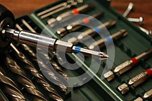 A screwdriver and a set of bits on a dark wooden table