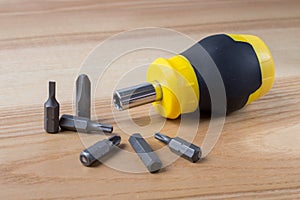 Screwdriver with set of bits on wooden table