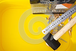 Screwdriver set, metal ruler, mallet, furniture screws, wooden dowels in yellow container
