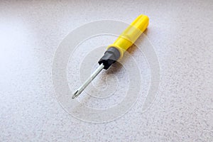 Screwdriver with yellow handle on gray background, top view, close-up, space for text