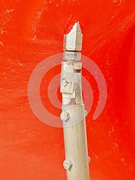 Screwed pole point of red plastic construction. Detail of decreased iron screws and metal tube in outdoor red equipment