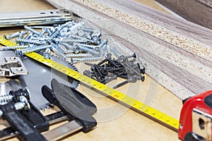 Screws, confirmations for furniture, tape measure, clamp, lie on the table. Furniture production photo