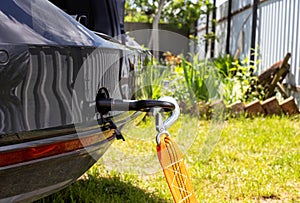 Screws in a tow hook in the car and an orange tow rope for towing, close-up, industrial