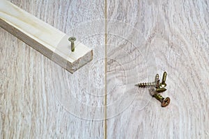 Screws and wooden bar on the table.